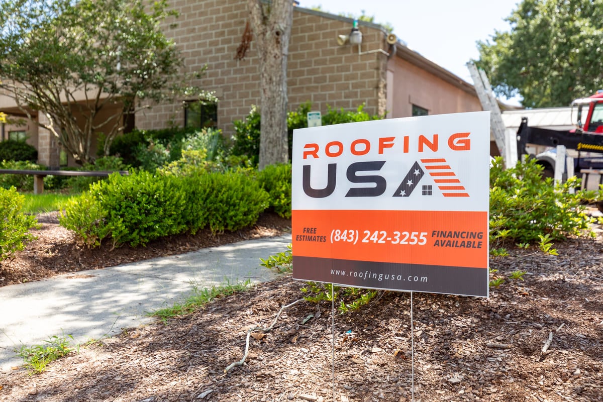 A Roofing USA sign in front of a commercial roofing project