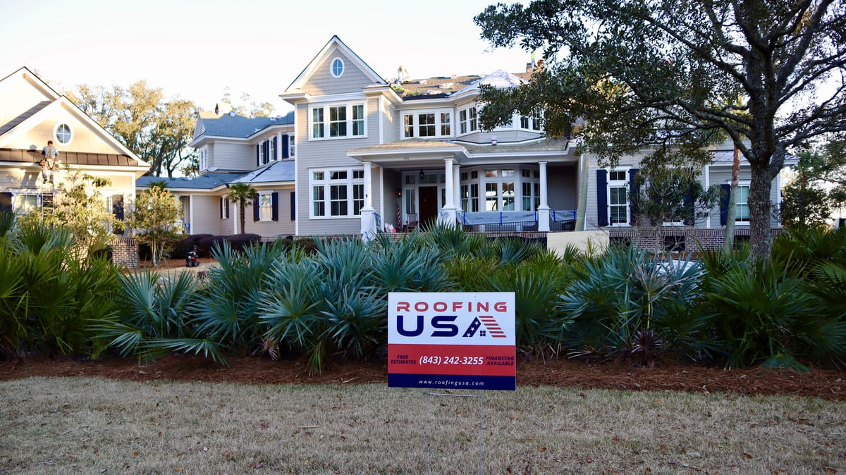 A Roofing USA sign in front of a residential roofing project