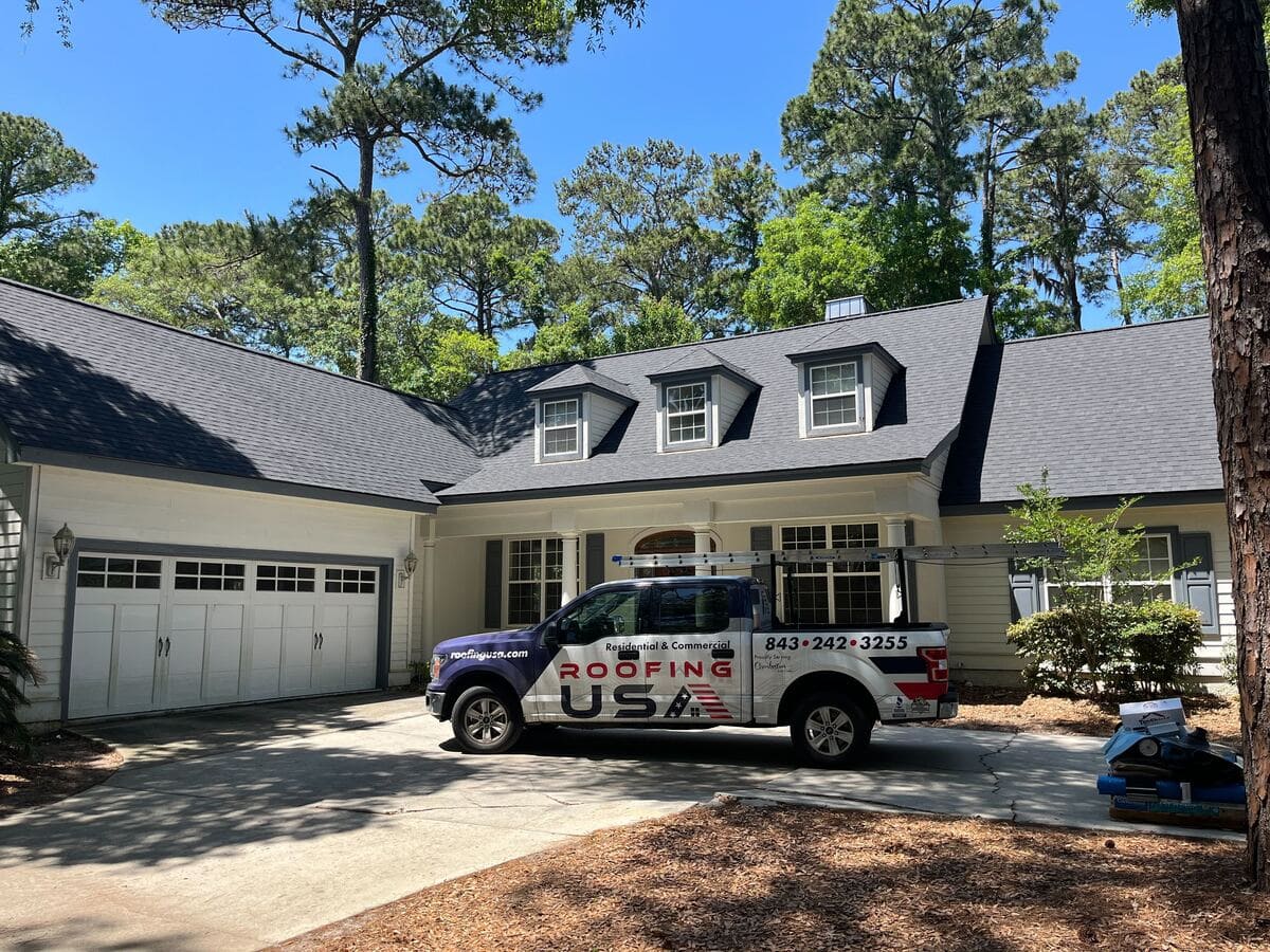 A Roofing USA truck in front of a completed residential roof