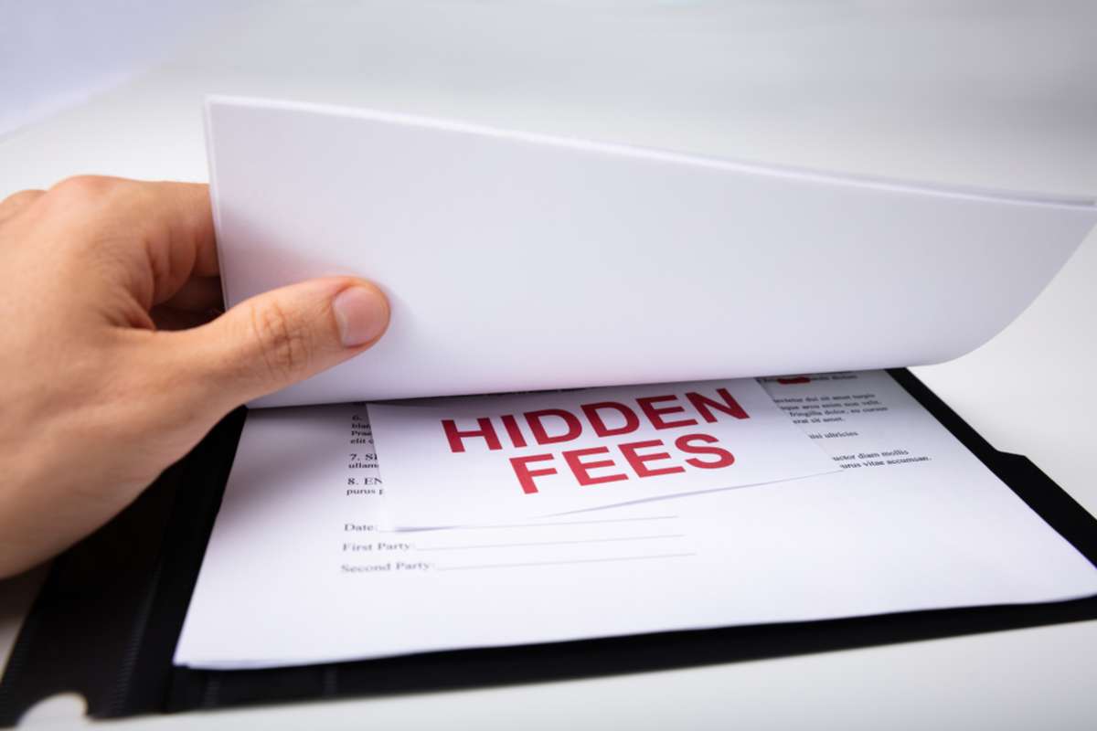 A hand finds Hidden Fees underneath papers, roofing quotes concept