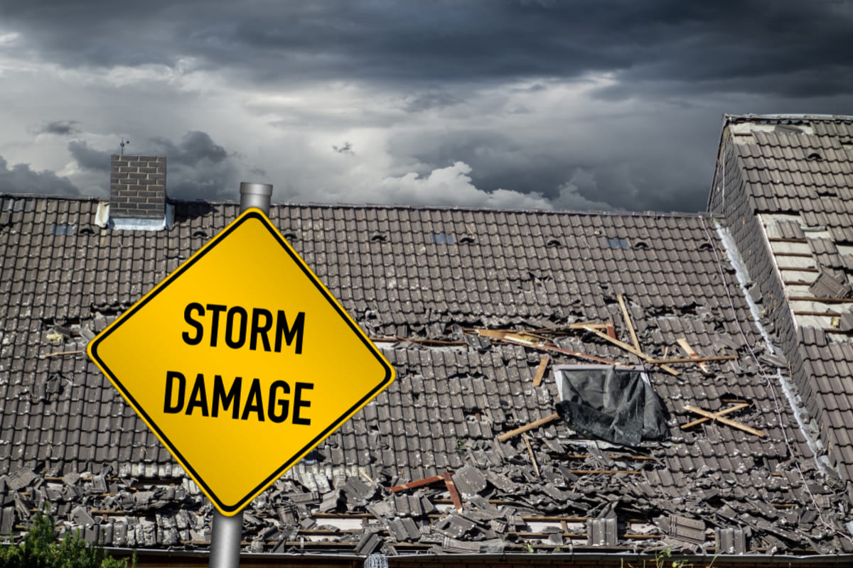 A roof with damaged shingles and the word storm damage, roof damage concept