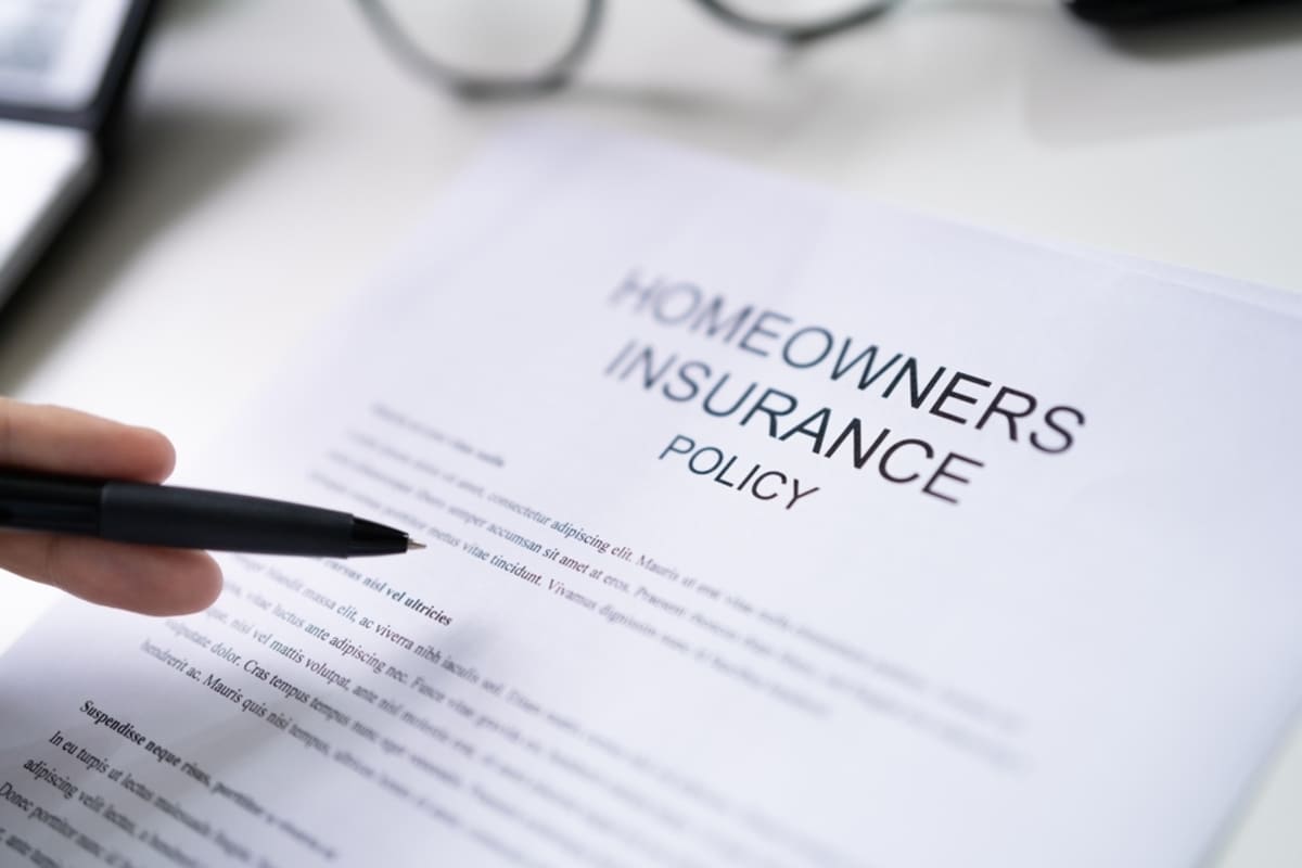 Close-up of a hand with a pen and homeowners insurance coverage policy