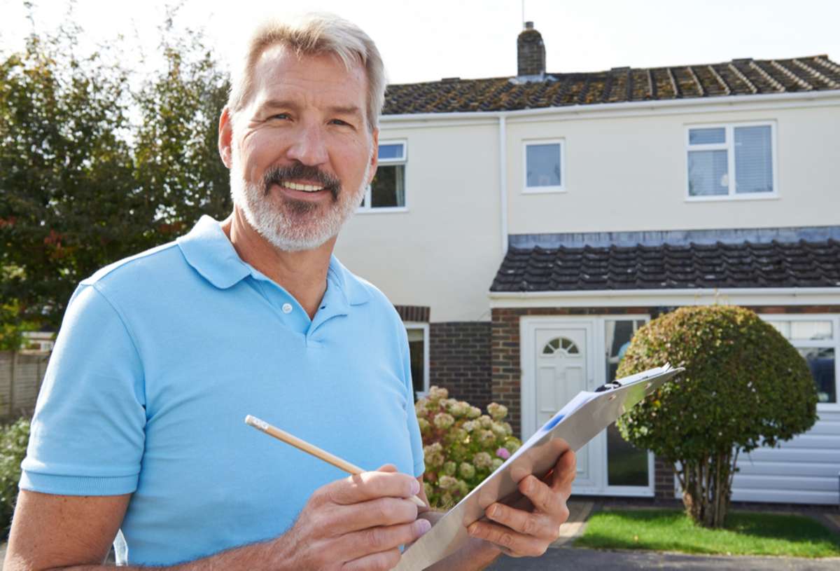 Man writing an estimate outside a home, roofing quotes concept