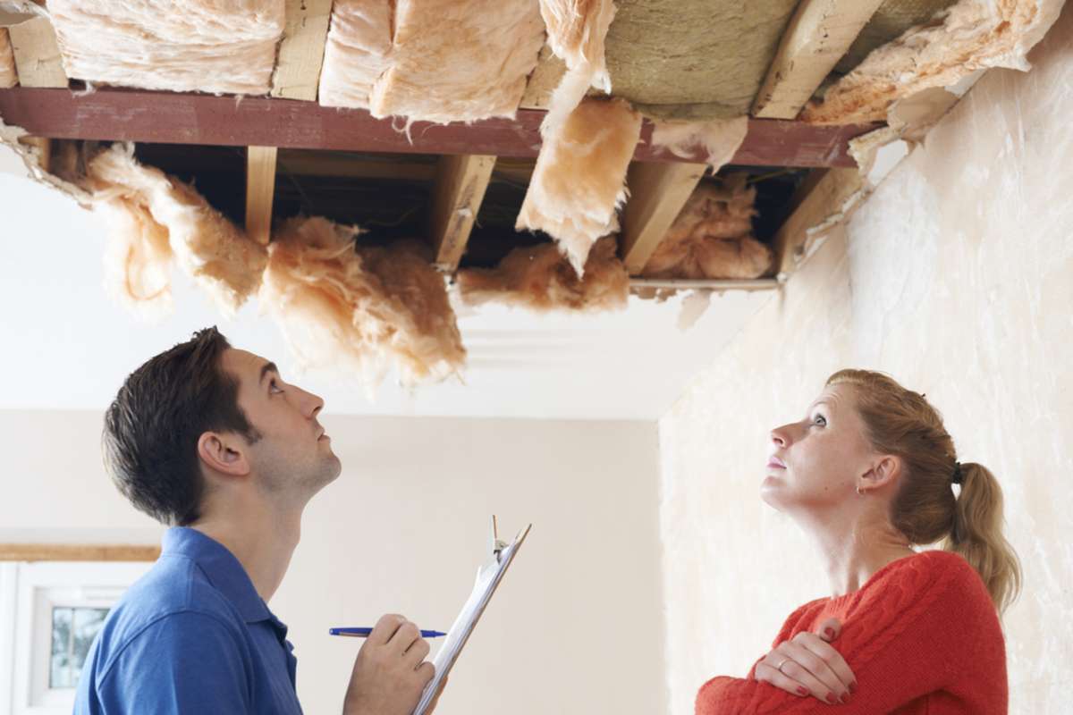 Roofer and homeowner examine ceiling damage, roofing companies near me free estimates concept