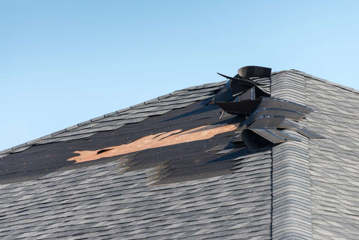Wind-damaged roof, roofing insurance claim concept