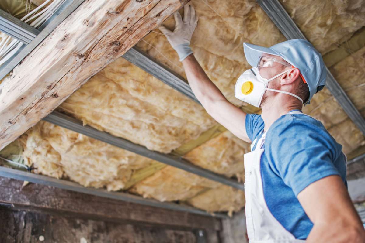 A man inspects attic insulation during a roof inspection. 