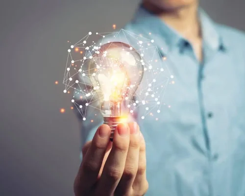 A_man_holding_a_lightbulb_with_geometric_shapes_around_it