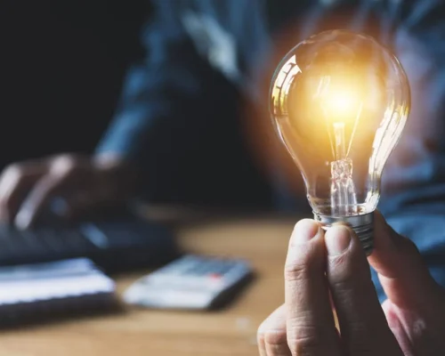 A_person_holding_a_lit-up_lightbulb,_understanding_the_concept_of_commercial_roofing_systems_concept
