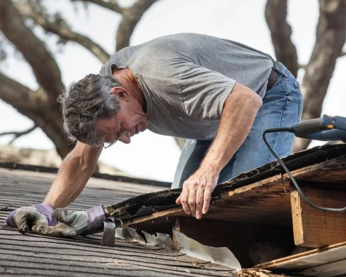Close_up_view_of_man_using_removing_rotten_wood_from_leaky_roof